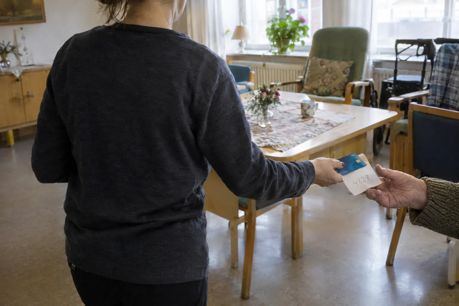 Illustration: en anonym person som räcker fram ett bankkort och en lapp med en kod